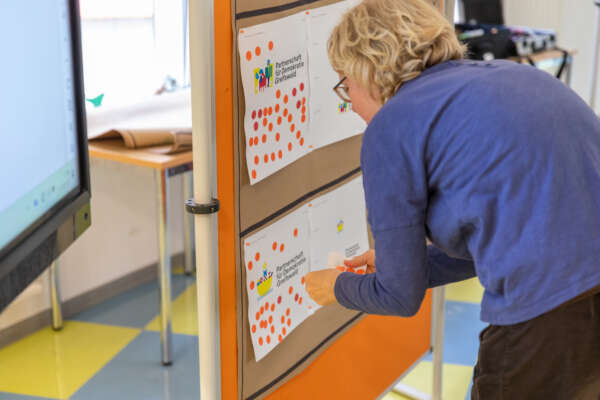 eine person beklebt an einer pinnwand verschiedene logoentwürfe der pfd mit punkten eine person beklebt an einer pinnwand verschiedene logoentwürfe der pfd mit punkten