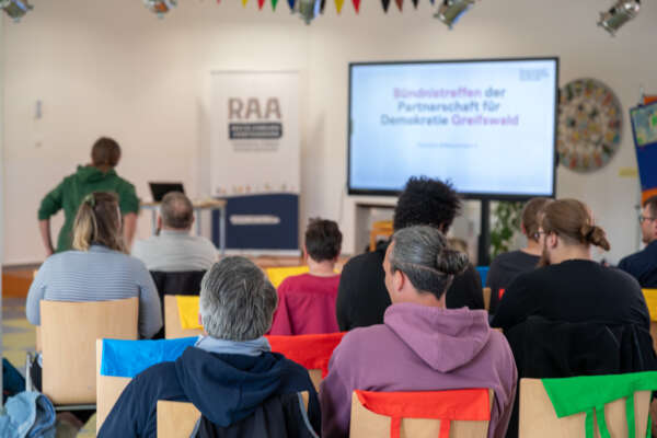 mehrere personen sitzen in einem veranstaltungsraum und verfolgen ein bündnistreffen mehrere personen sitzen in einem veranstaltungsraum und verfolgen ein bündnistreffen